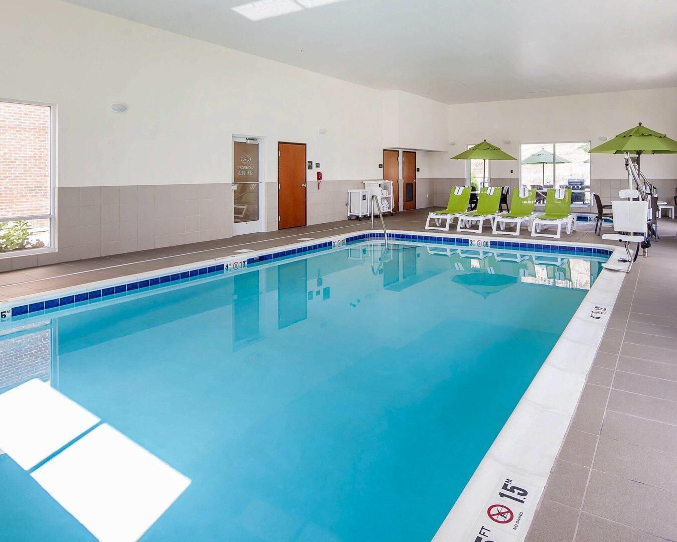 A swimming pool with lounge chairs and umbrellas, a door labeled 'Room 23', and a tiled floor.