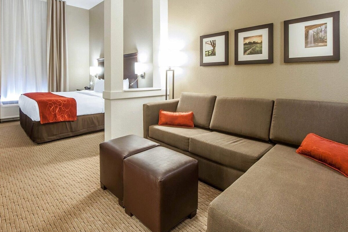 A hotel room with a bed, a sofa, a coffee table, and three framed pictures on the wall.