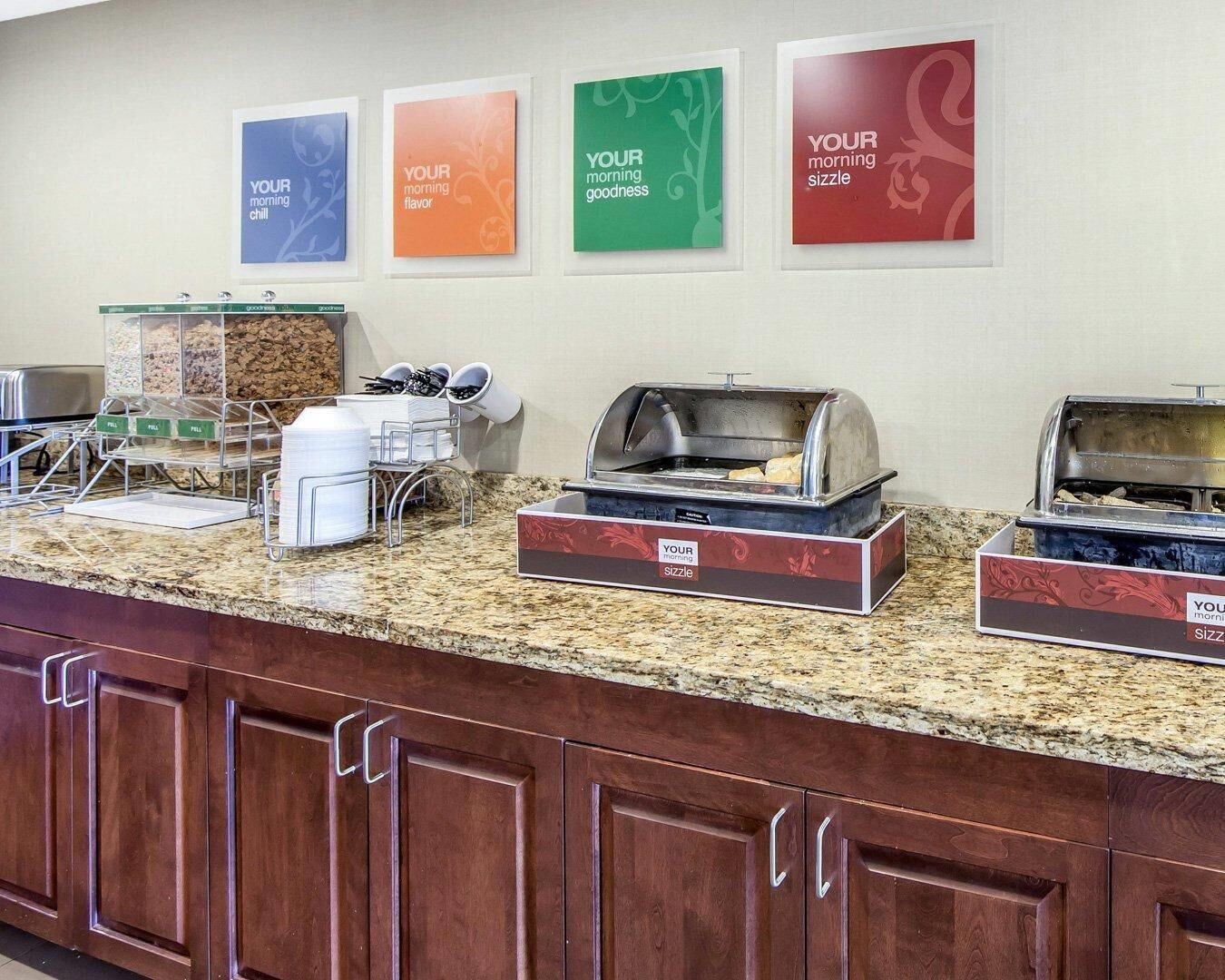 A breakfast buffet area with labeled containers for different food items, a coffee station, and a toaster.