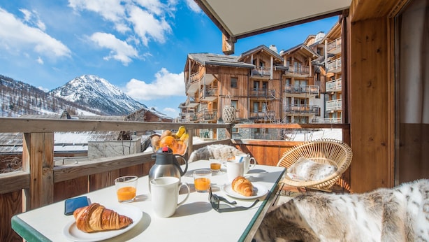 Un balcón con alimentos para el desayuno, un croissant y vistas a la montaña.
