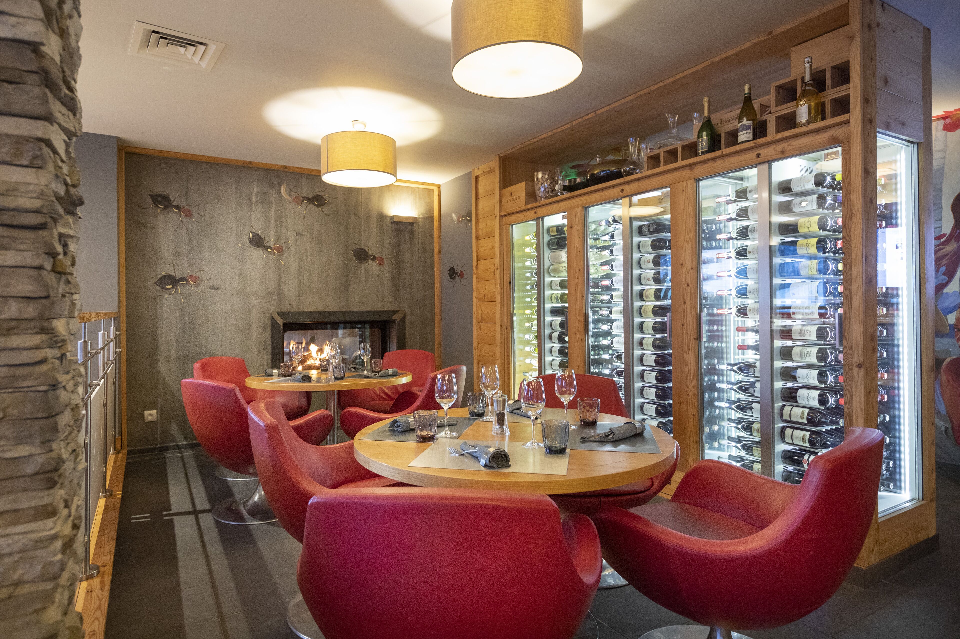 Un restaurant avec des chaises rouges, une table en bois et un réfrigérateur à vin.