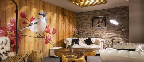 A modern living room with a wooden wall mural, a white leather sofa, a wooden coffee table, and a floor lamp.