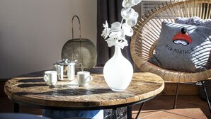 Una habitación acogedora con una mesa redonda de madera, una silla de mimbre y vistas a montañas nevadas a través de una ventana.