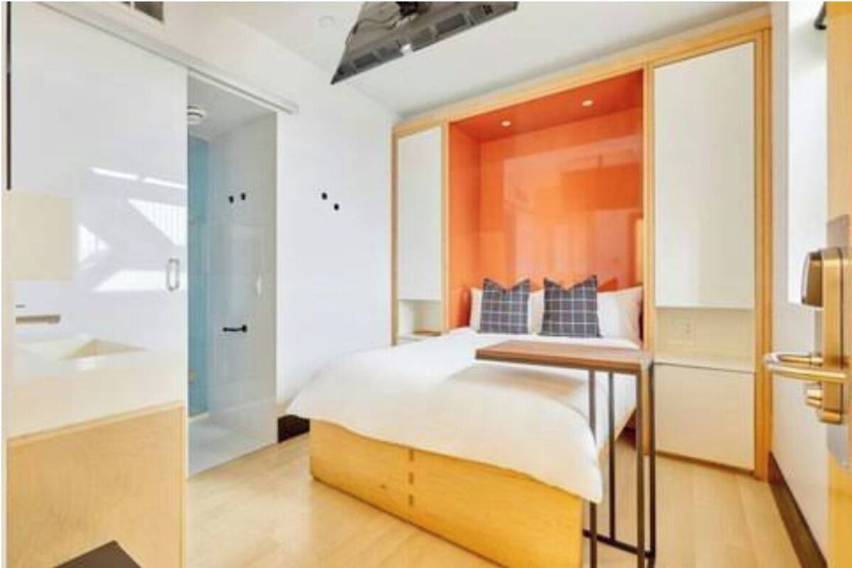 Una habitación de hotel moderna con una cama, un escritorio pequeño y un baño.