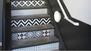 Un escalier dont les marches sont décorées de motifs, menant à un palier.