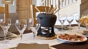Mesa de jantar posta com copos de vinho, pratos e talheres, com uma escadaria de madeira ao fundo.