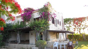 Une maison à deux étages dotée d’un patio, d’un mur en pierre et d’une pergola.