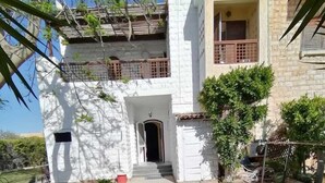 Un bâtiment à deux étages, doté d’une entrée carrelée et d’un petit jardin.
