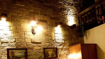 A room with a stone wall, a bed with a metal headboard, and a wooden cabinet.
