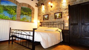A bedroom with a bed, stone walls, and a mural of a landscape. - Chalet sul lago Hotel In Montagna (Moncenisio)