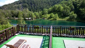 A deck with a view of a lake surrounded by forest. - Chalet sul lago Hotel In Montagna (Moncenisio)