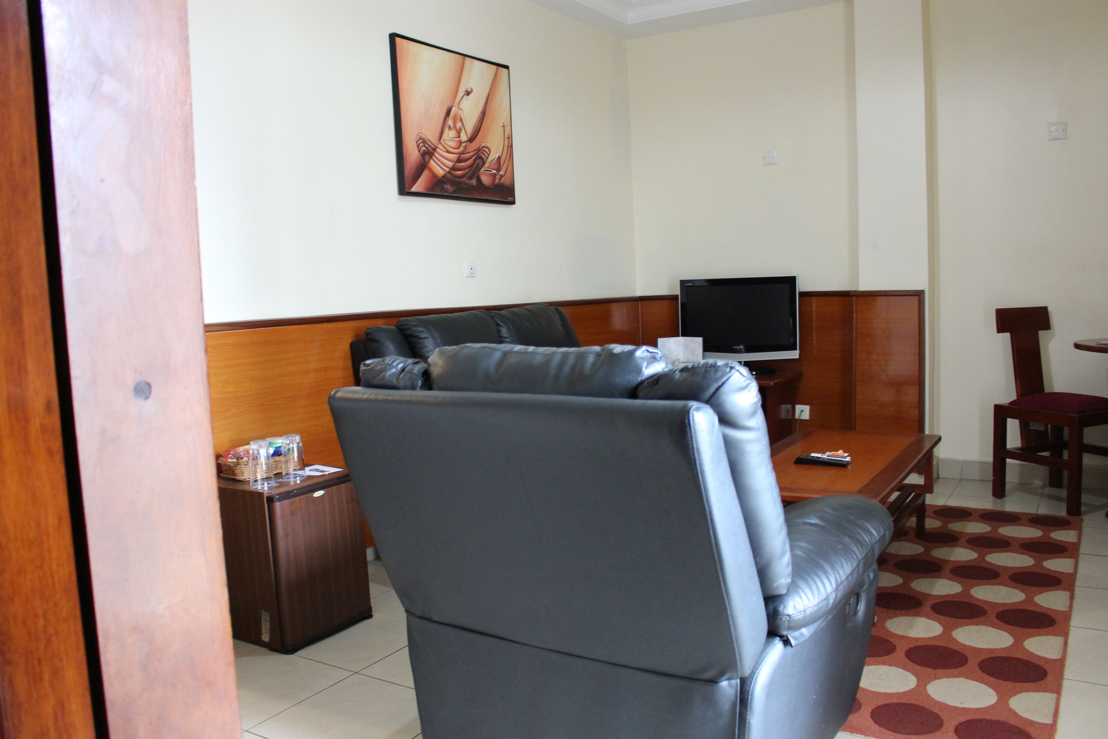 Una sala de estar con un sofá de cuero, un televisor, una mesita y un mueble de madera.