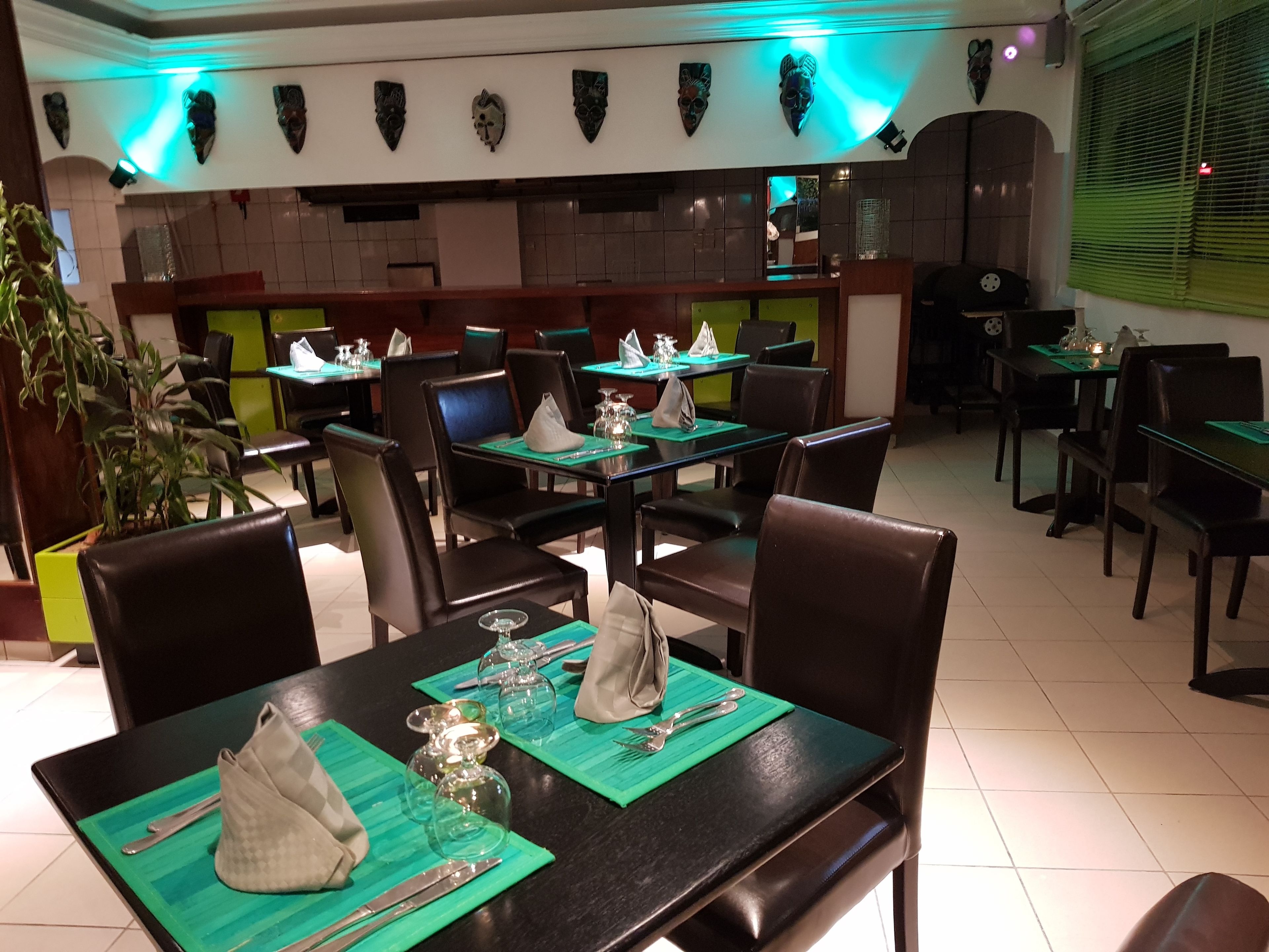 A restaurant with tables set for dining, featuring green placemats, cutlery, and glassware.