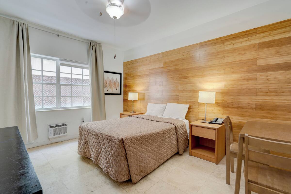 A hotel room with a bed, bedside tables, a desk, and a chair.