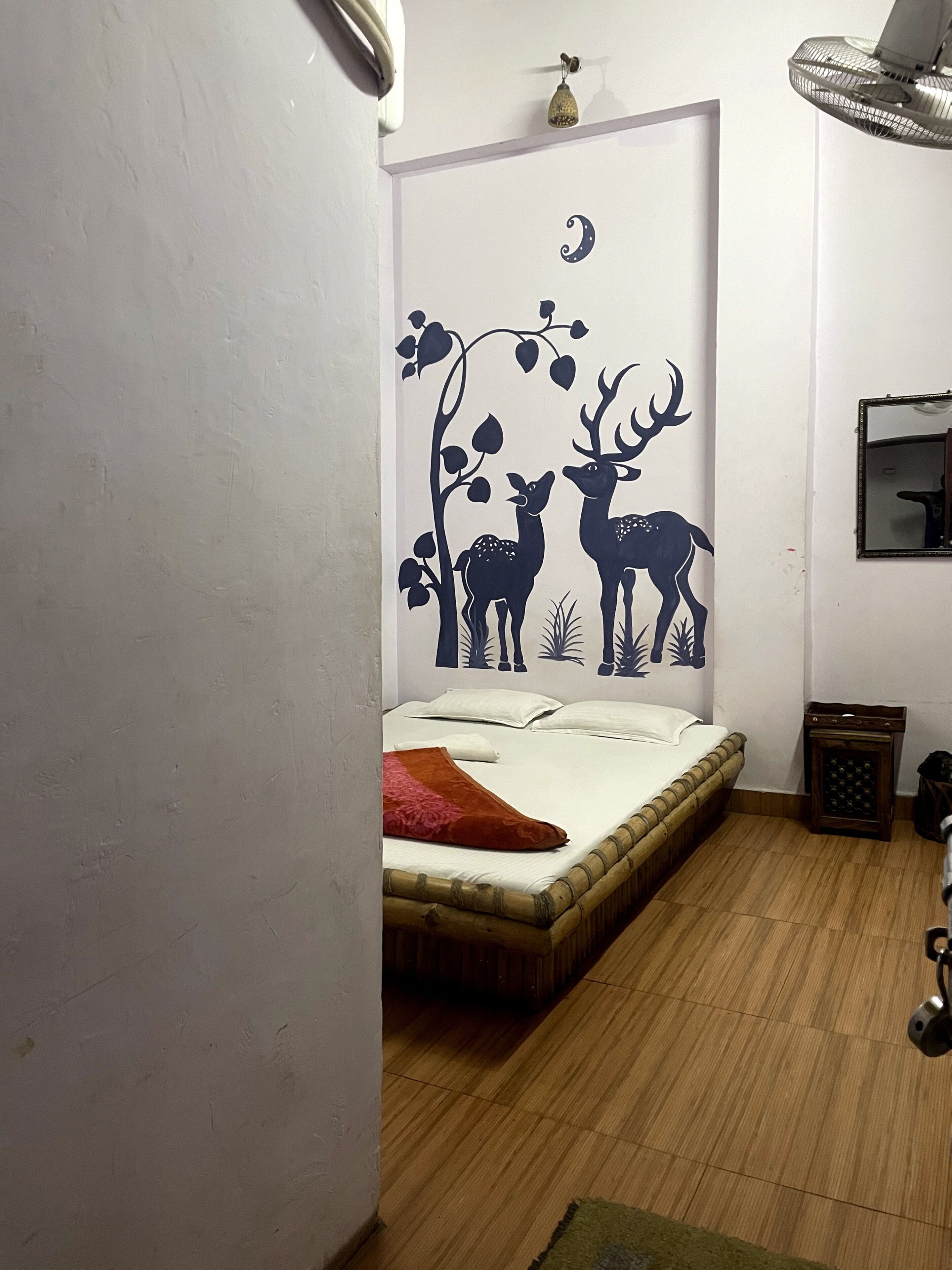 Une chambre à coucher avec un lit, une décoration murale représentant des cerfs, une petite table de chevet et un miroir.