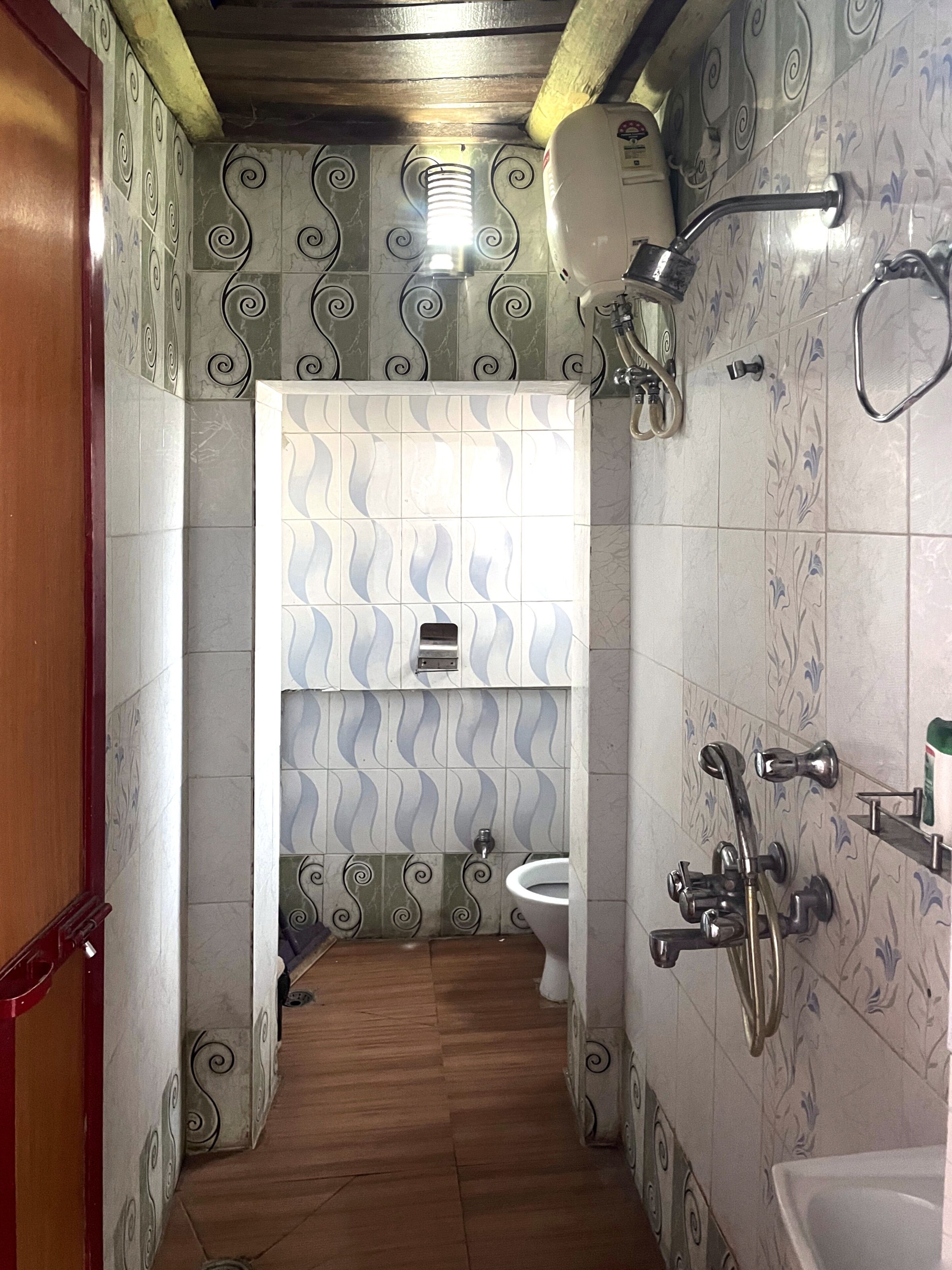 A bathroom with patterned tiles, a toilet, a shower, and a sink.