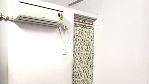 A room with a bed, an air conditioning unit, and a patterned door. - Shri Guest House (Varanasi)