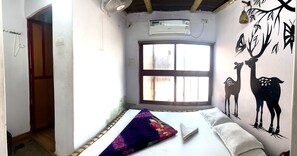 Un dormitorio con cama, aire acondicionado, una ventana y un mural de ciervos.