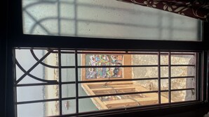 A window with a grid pattern, a view of a building with a colorful mural, and a clear sky. - Shri Guest House (Varanasi)