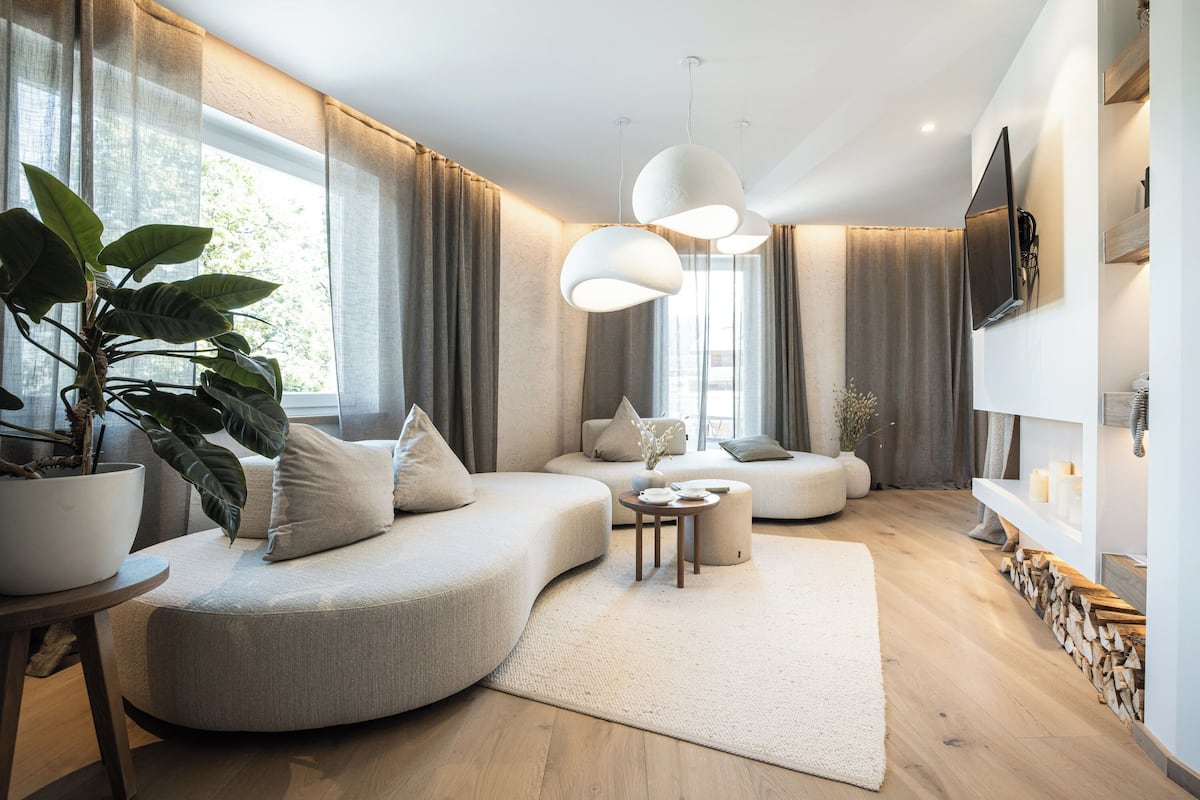 A modern living room with a curved sofa, a round coffee table, and a large potted plant.