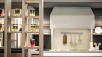 A modern kitchen with wooden shelves holding jars, a white hood, and hanging utensils.