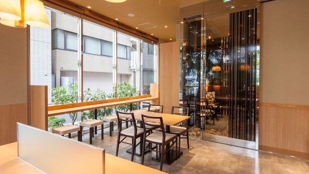A modern interior with wooden tables and chairs, large windows, and a glass partition. - APA Hotel Ginza Kyobashi Minami (Tokyo)