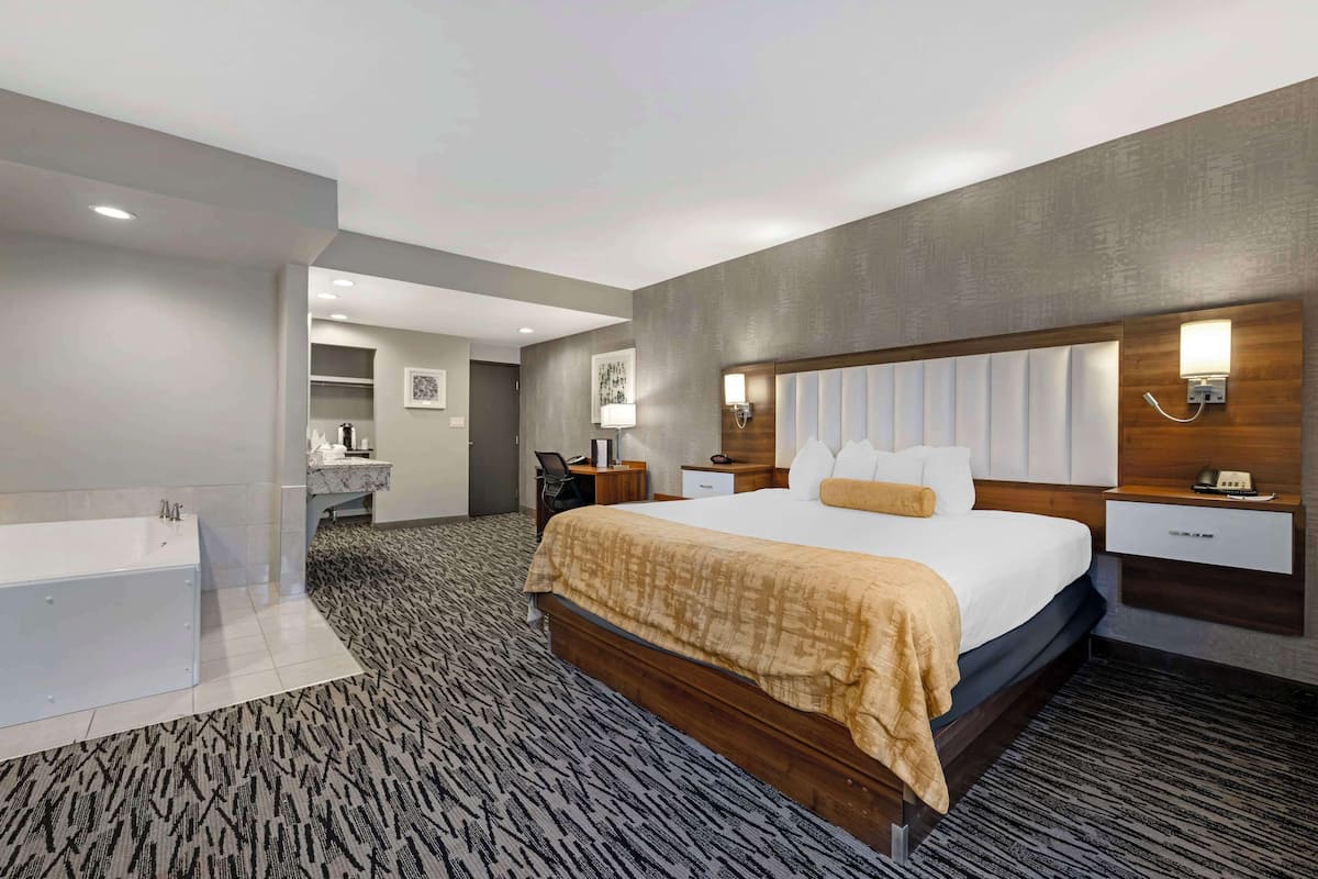 Habitación de hotel moderna con una cama grande, baño independiente y una pequeña zona de escritorio.