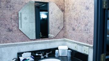 A bathroom with a black sink, a mirror, and a trash bin.