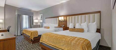 A hotel room with two beds, a desk, a chair, a nightstand, and a window with curtains.