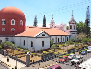 Une église dotée d’un grand dôme rouge et de murs blancs, entourée d’une clôture et de verdure.