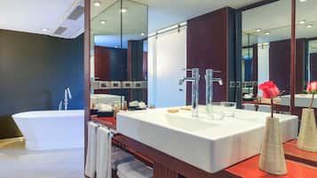 Un baño moderno con una bañera independiente, un tocador grande con espejo y un tocador de madera con toallas.