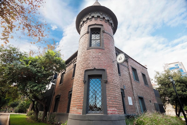 Una torre de ladrillo con un turretín y una ventana con diseño de cuadrícula.