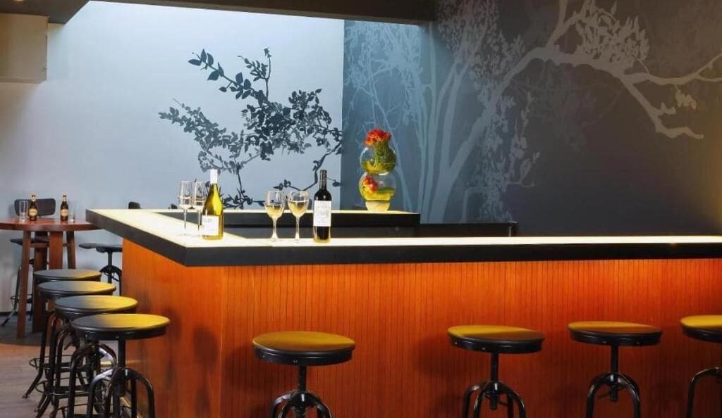 A bar area with a wooden counter, bar stools, and a decorative vase.