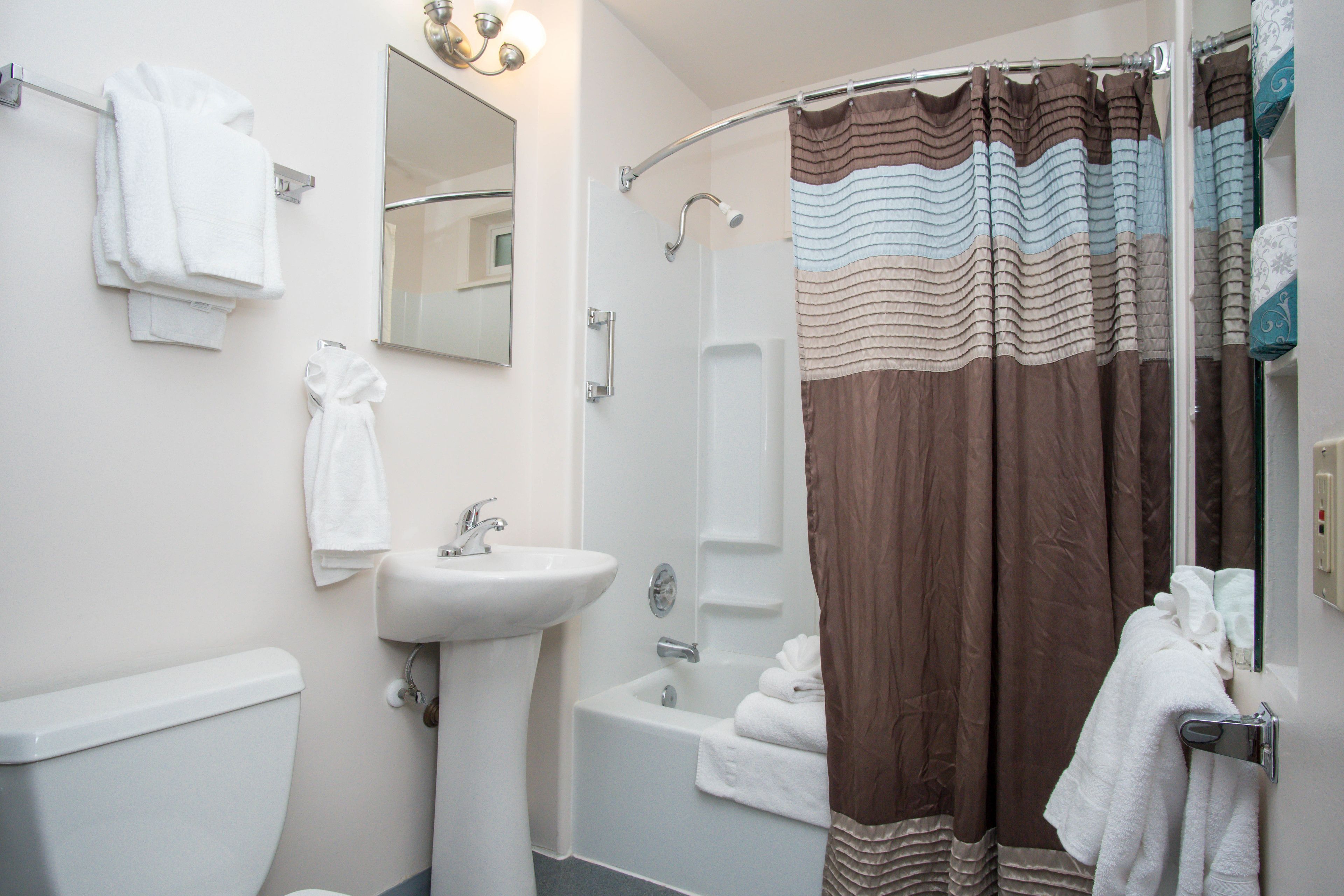 A bathroom with a sink, toilet, bathtub, and shower curtain.