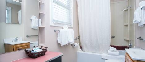 A bathroom with a sink, mirror, towel rack, shower, and toilet.