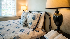 Un dormitorio con cama, lámpara y ventana con persianas.