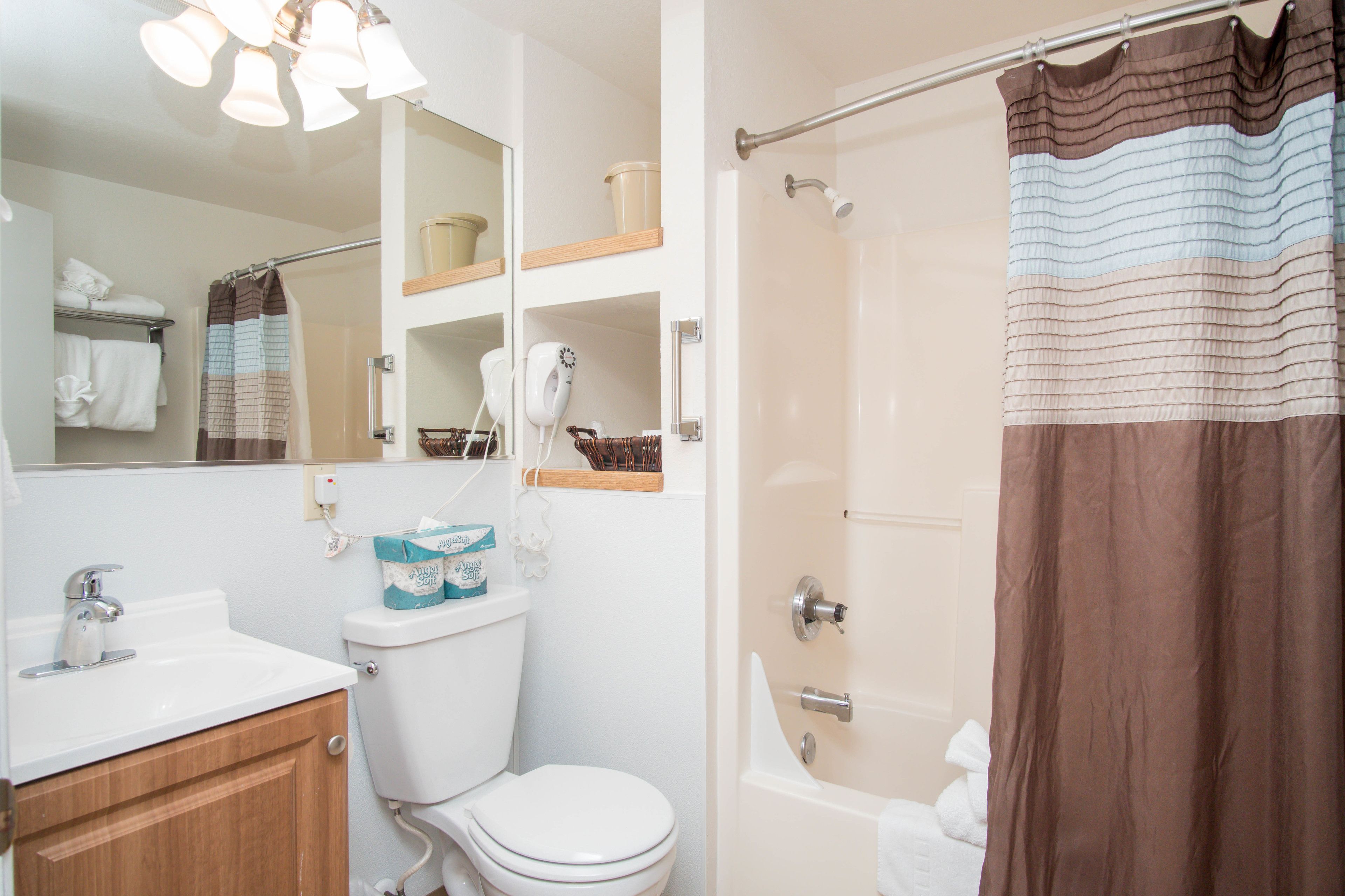 A bathroom with a toilet, sink, mirror, and shower curtain.