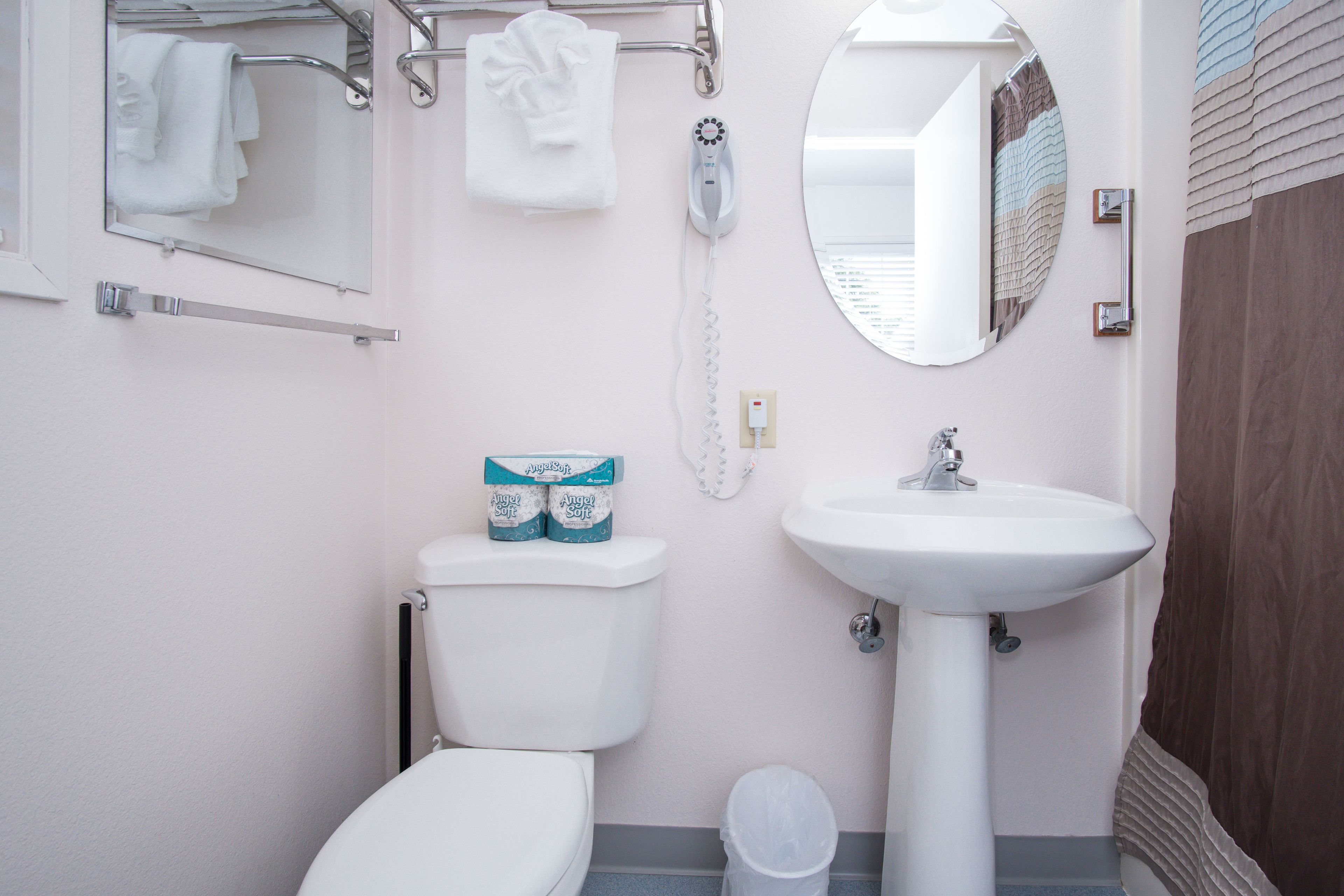 Une salle de bain équipée de toilettes, d’un lavabo, d’un miroir et d’un porte-serviettes.
