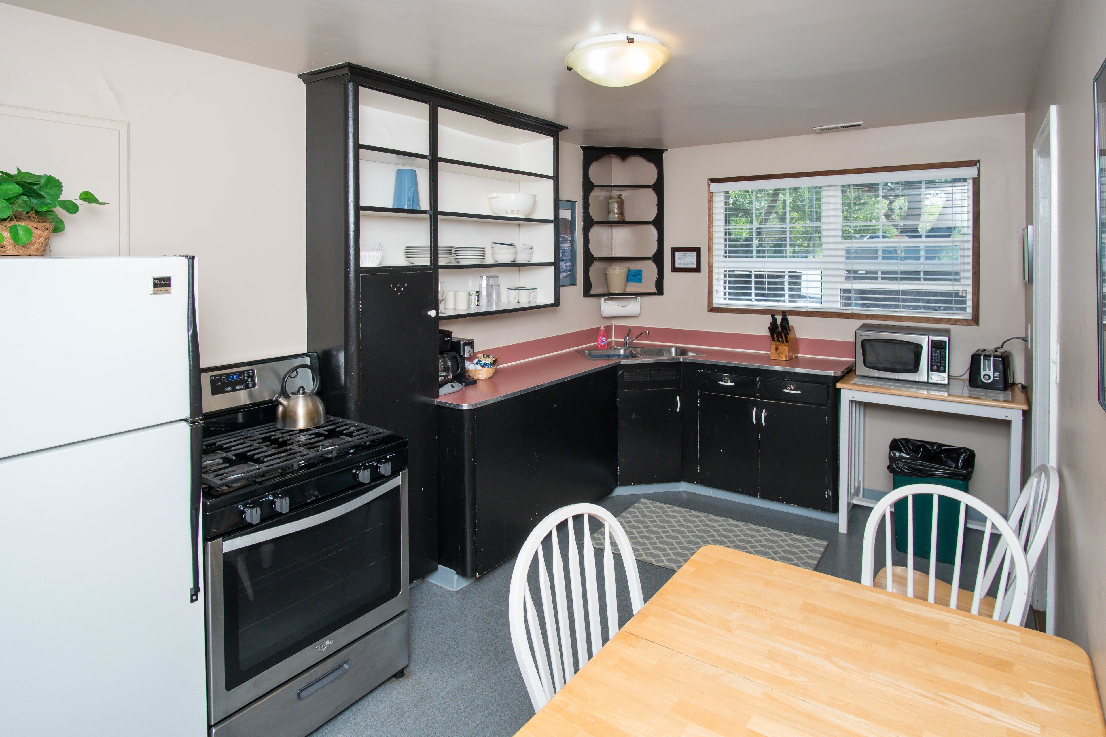A compact kitchen with a stove, oven, microwave, and a dining table with chairs.