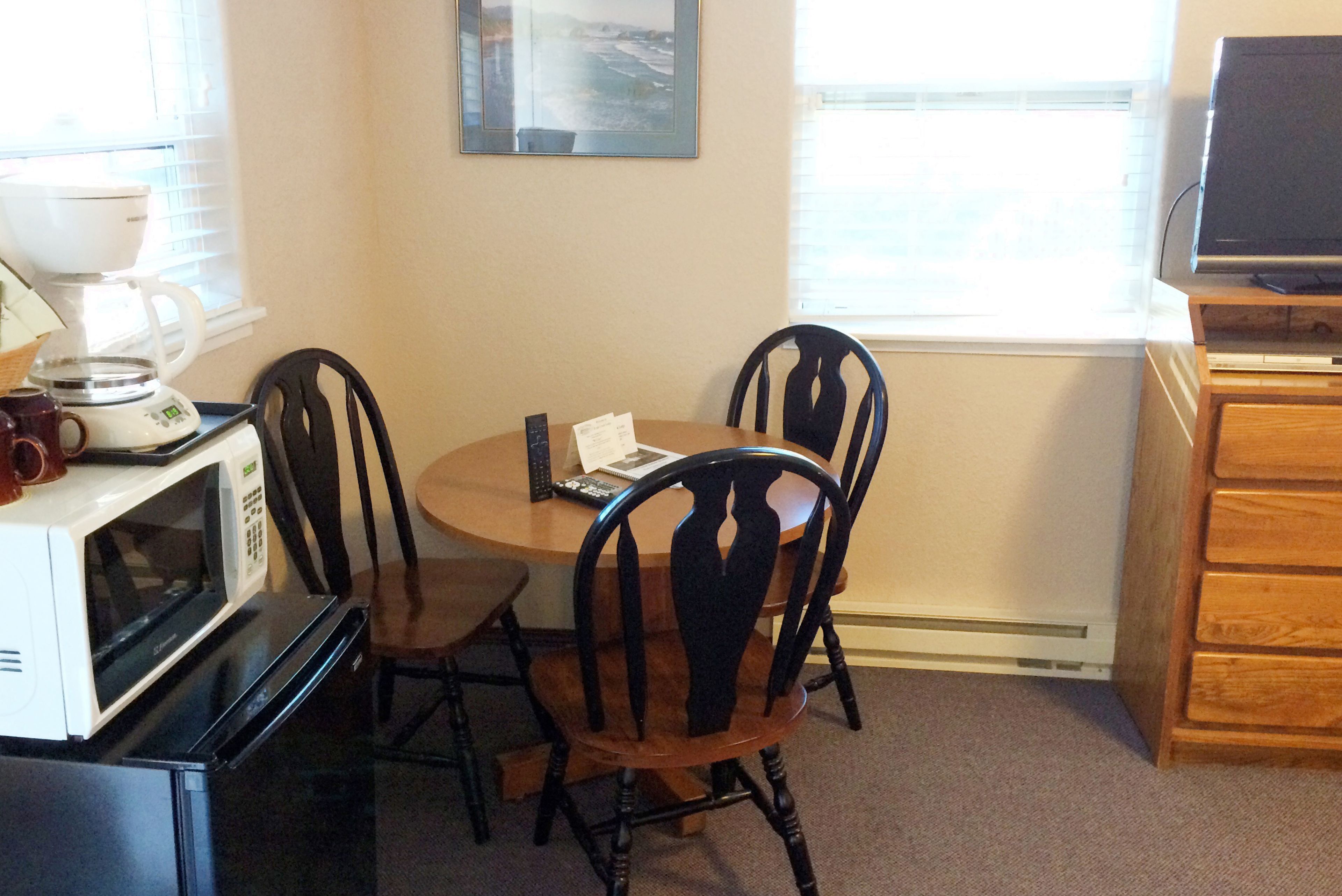 A dining area with a table, chairs, a microwave, and a television.