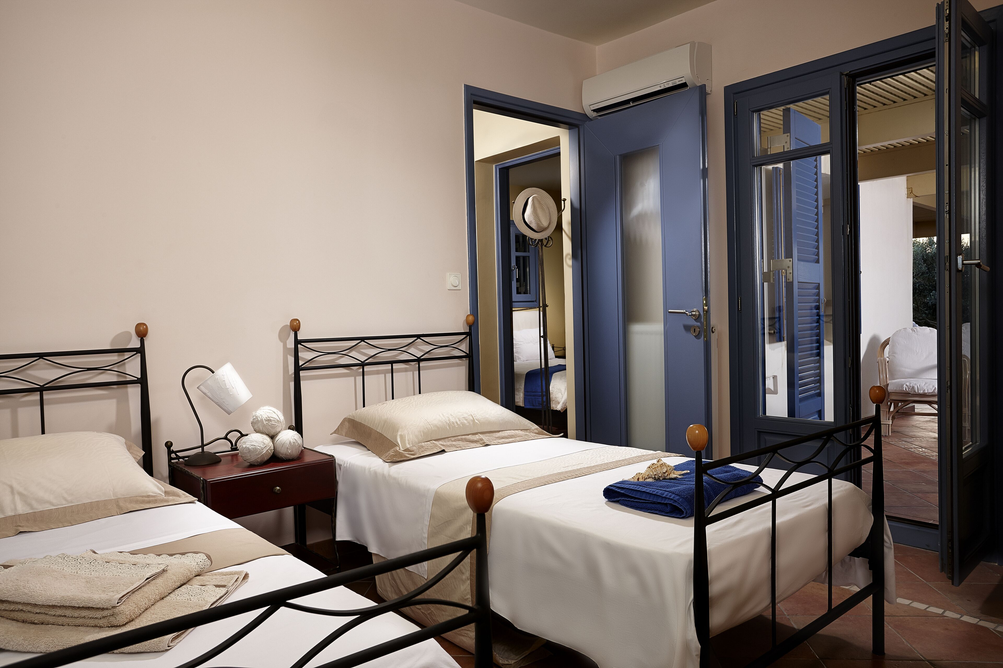 Une chambre d’hôtel avec deux lits simples, une table de chevet avec une lampe et une armoire.