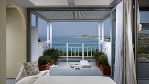 A bedroom with a large bed, a view of the sea, and a balcony with potted plants. - Villa Paradise (Naxos)