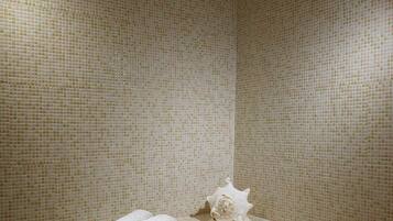 Bathroom features a mosaic wall design, a shelf with two towels, and a starfish decoration.
