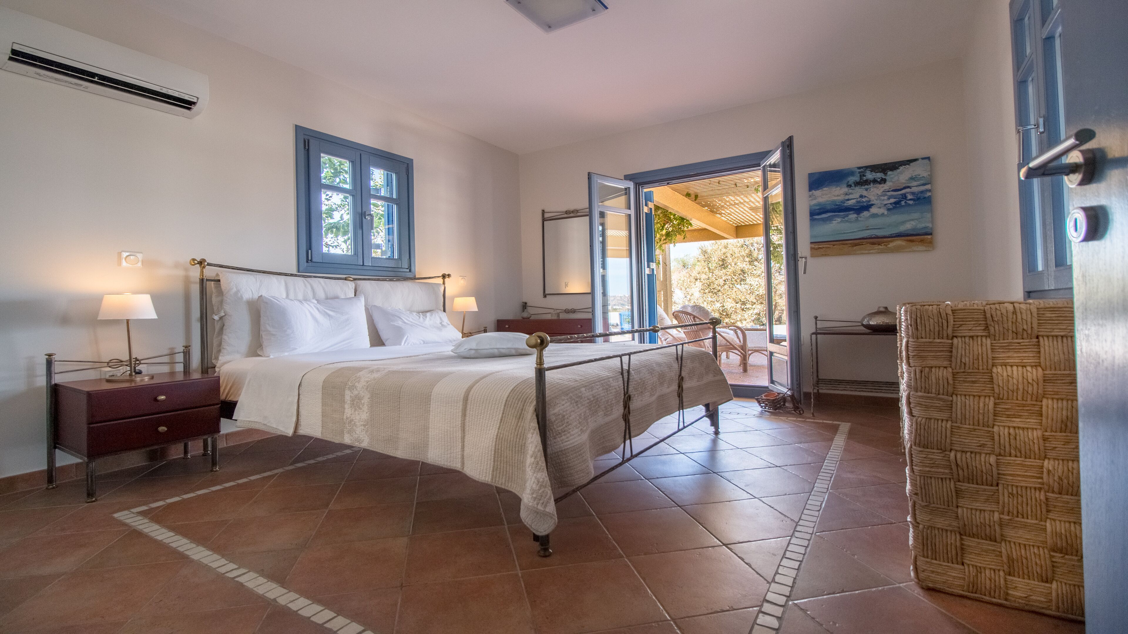 A bedroom with a bed, bedside tables, a window, and a view of the outdoors.