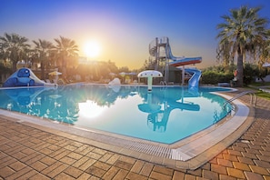 Una piscina con tobogán y zona de juegos para niños.