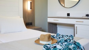 Una habitación de hotel con cama, mesita de noche, espejo y cómoda.
