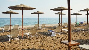 Una playa con filas de tumbonas y sombrillas de paja.