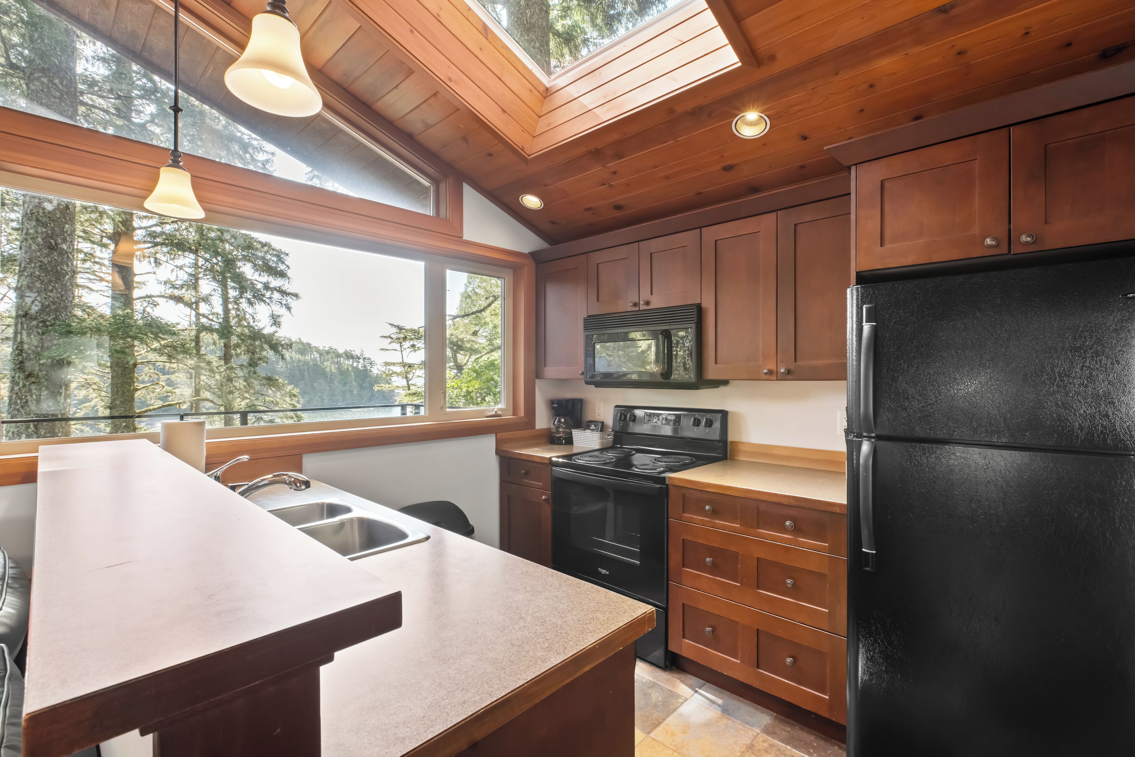 Une cuisine moderne avec des meubles en bois, un réfrigérateur noir, une cuisinière et un four à micro-ondes.