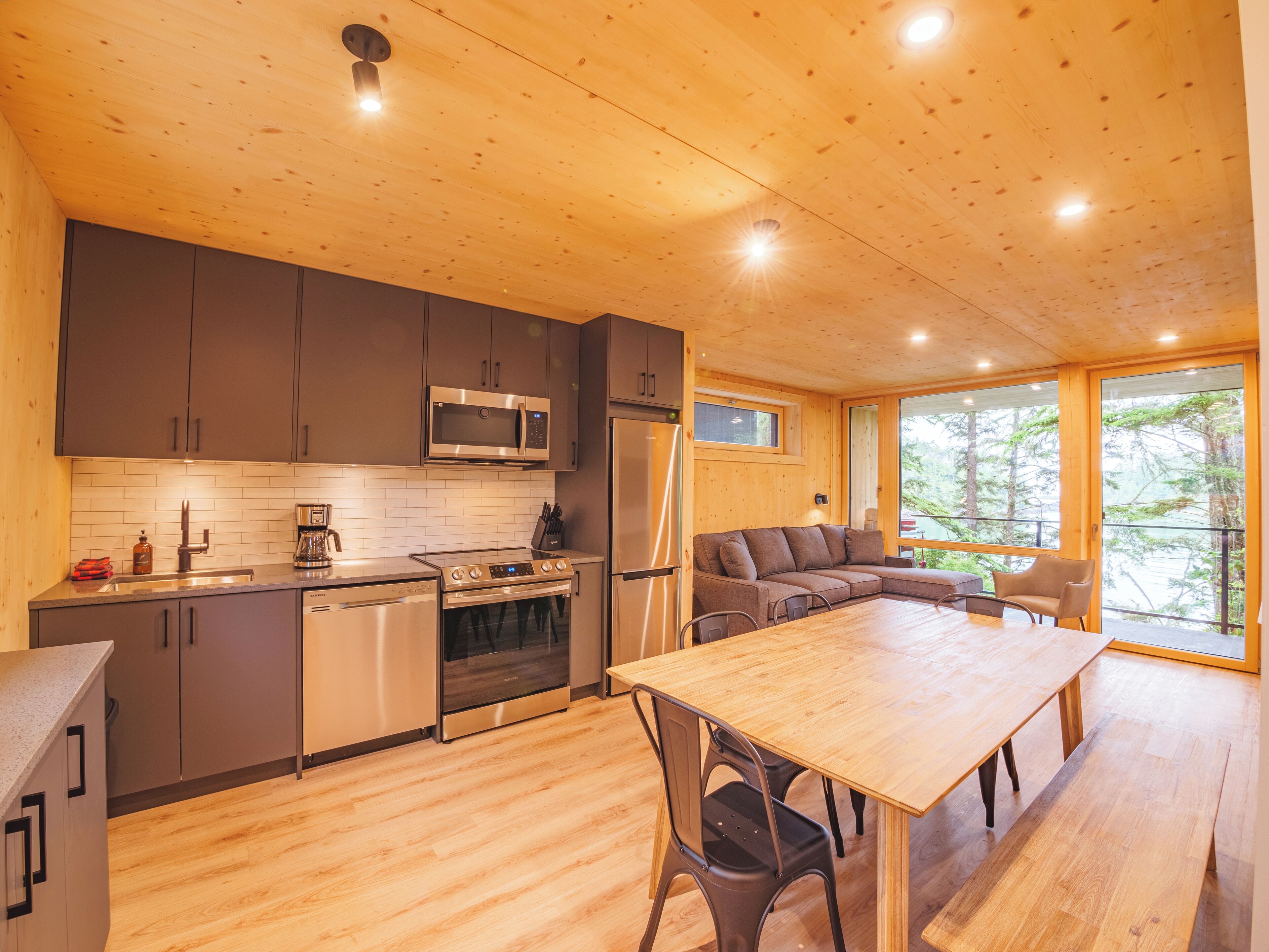 A modern kitchen with wooden cabinets, stainless steel appliances, and a dining area with a wooden table and chairs.
