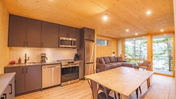 A modern kitchen with wooden cabinets, stainless steel appliances, and a dining area with a wooden table and chairs.